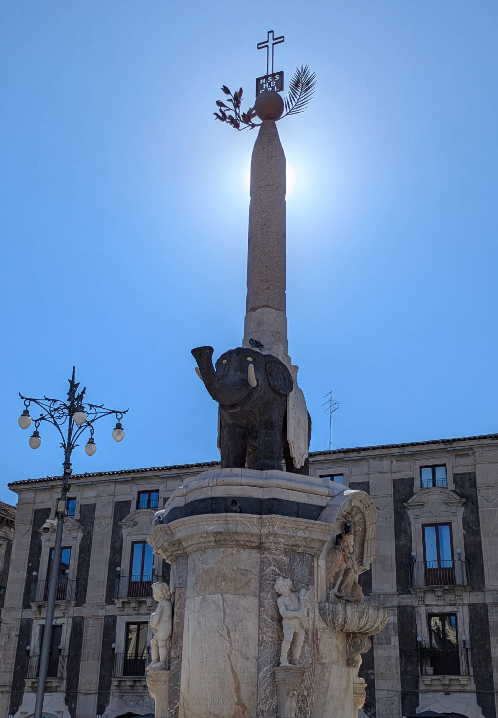 Der Elefantenbrunnen in Catania: Ein schwarzer Elefant auf einem Marmorsockel, der auf seinem Rücken einen mit einem Kreuz geschmückten Obelisken trägt.